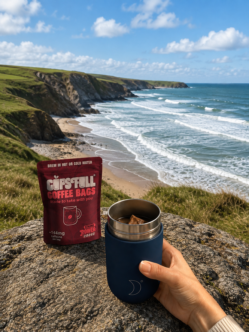 Cups Full Power pouch and travel mug on a clifftop above the sea