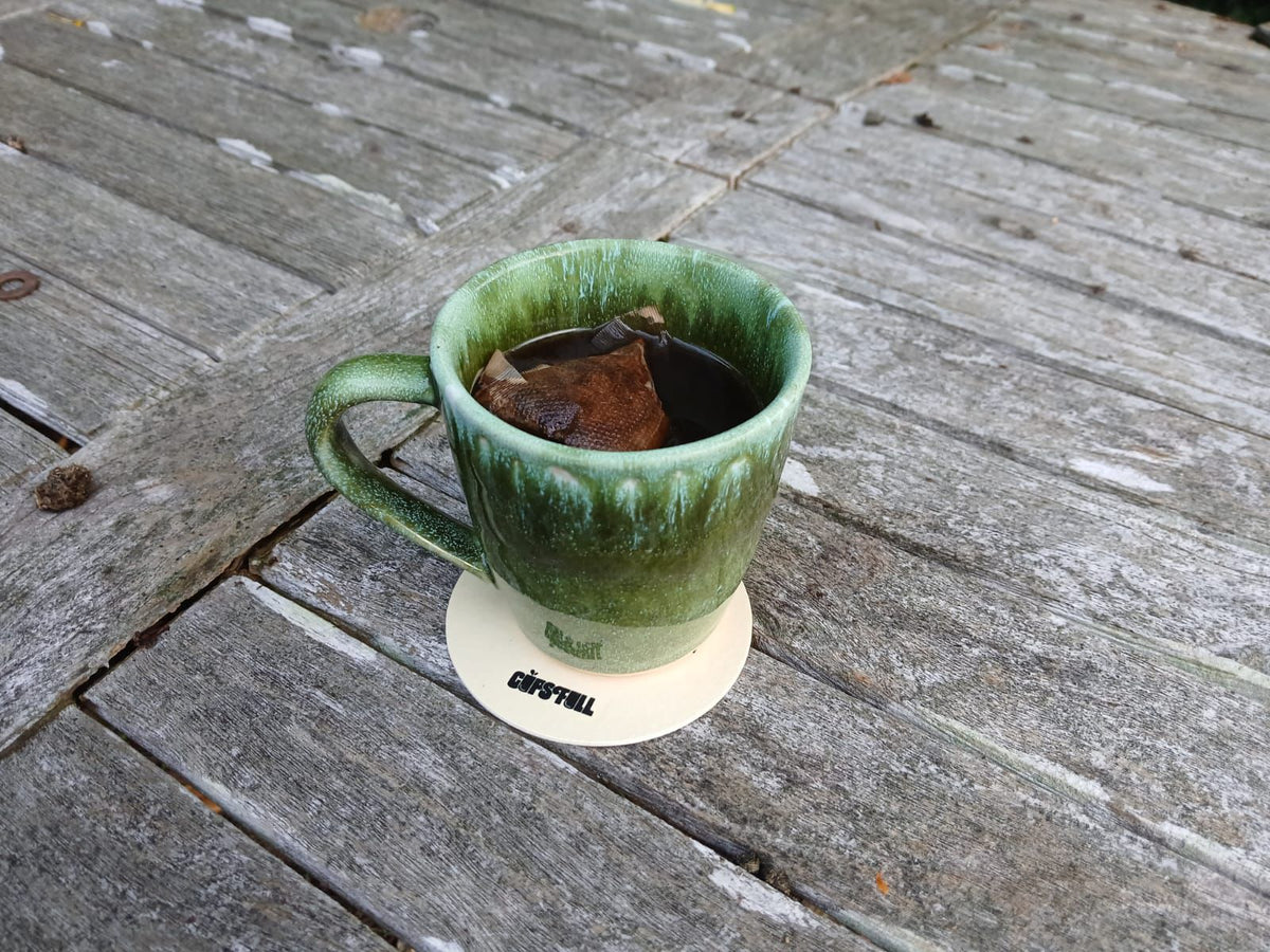 Cups Full coffee bag brewing in a green ceramic cup on a wooden table